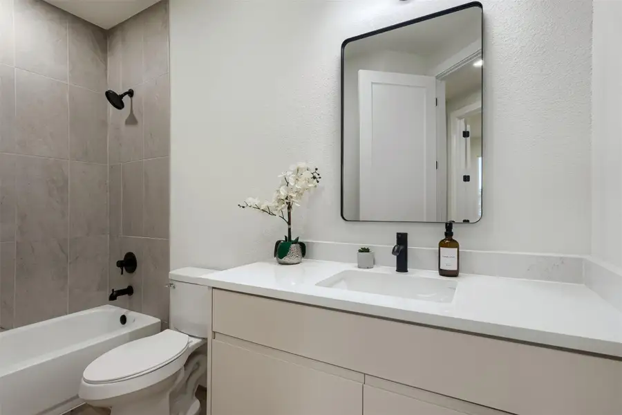 Stylish secondary bath with sleek black fixtures, quartz counters, and modern finishes