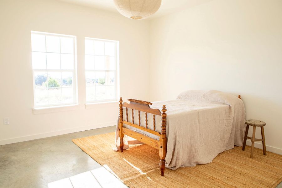Bedroom featuring baseboards and finished concrete floors Bedroom featuring baseboards and finished concrete floors