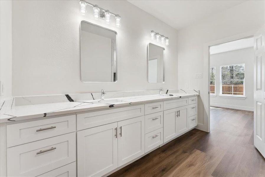 Bathroom featuring wood-style vinyl flooring and his and her sink