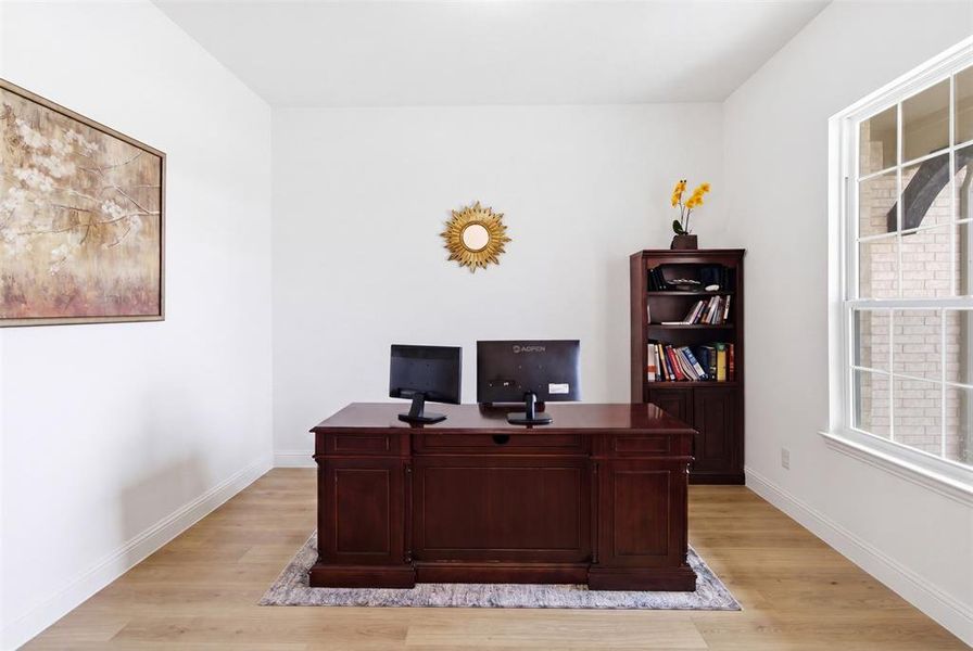 Dedicated space featuring light wood-finish flooring, white baseboards, and a large window with grilles