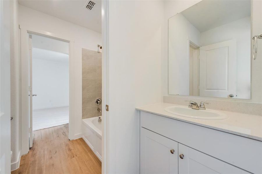 Bathroom with vanity, hardwood / wood-style flooring, and tiled shower / bath