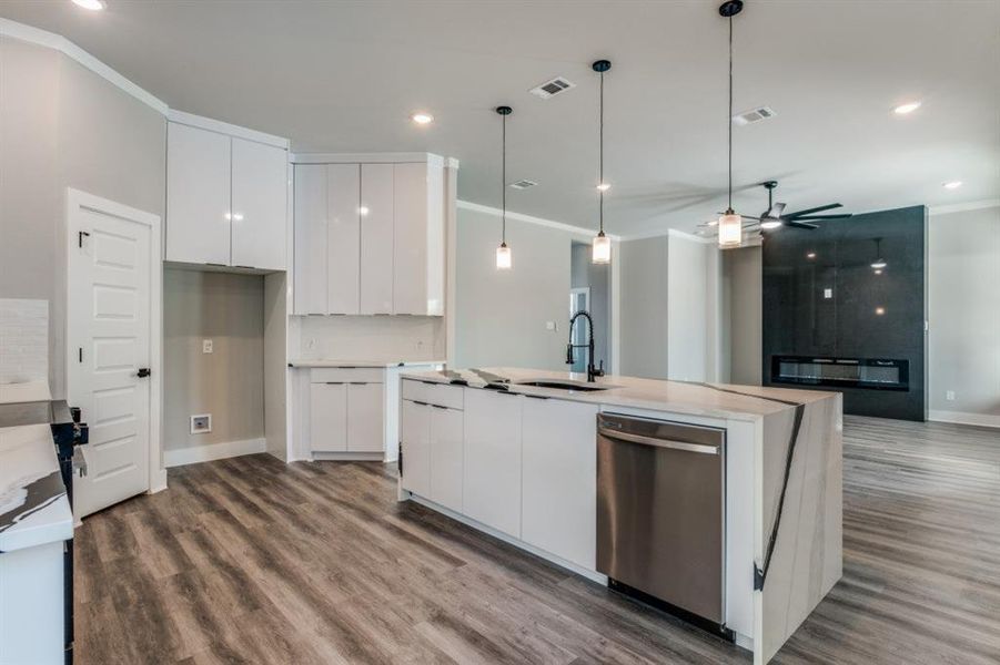 Kitchen with crown molding, modern cabinets, hanging light fixtures, stainless steel dishwasher, and recessed lighting