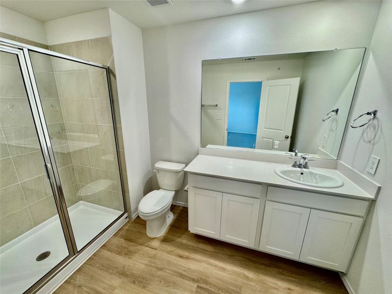 Full bath featuring vanity, light wood-style flooring, and a stall shower