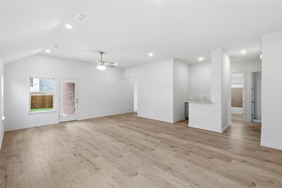 Spacious living area featuring vaulted ceilings, recessed lighting, wood-finish flooring, and a ceiling fan Spacious living area featuring vaulted ceilings, recessed lighting, wood-finish flooring, and a ceiling fan