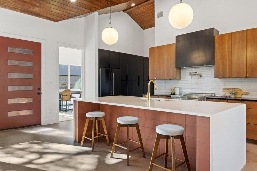 Kitchen featuring brown cabinets, a kitchen breakfast bar, decorative light fixtures, wooden ceiling, and a spacious island
