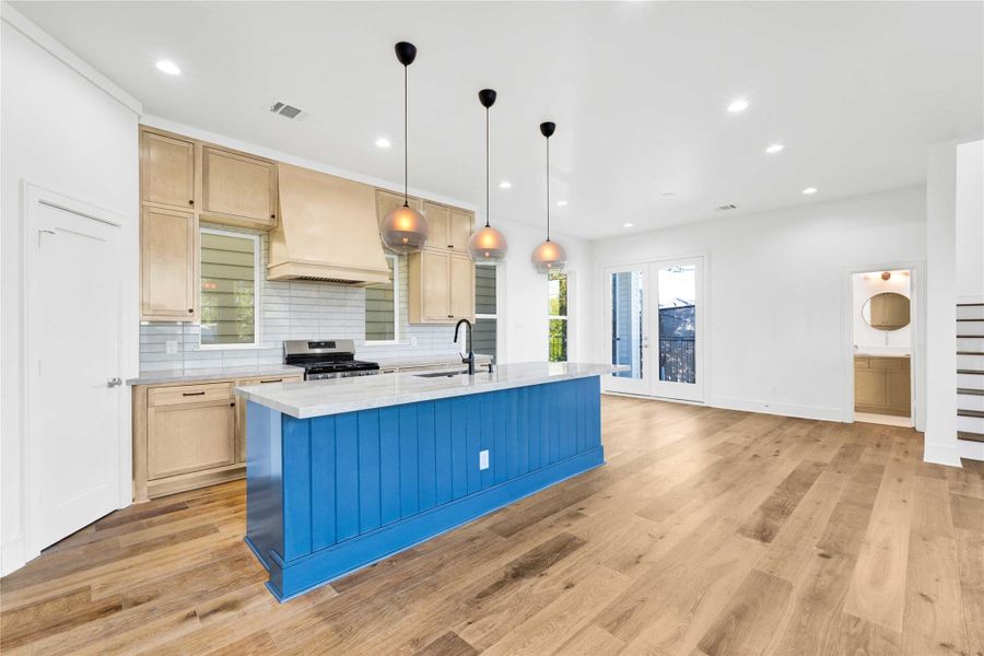 The kitchen features custom-built cabinets, Taj Mahal countertops, ample storage, and a walk-in pantry.