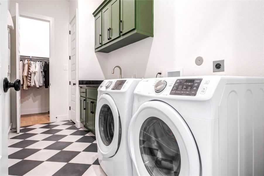 This laundry room features stylish green cabinetry, a sleek black countertop, and modern appliances. The space is well-lit and has a checkered floor, offering a functional and attractive area for laundry tasks. This laundry room features stylish green cabinetry, a sleek black countertop, and modern appliances. The space is well-lit and has a checkered floor, offering a functional and attractive area for laundry tasks.