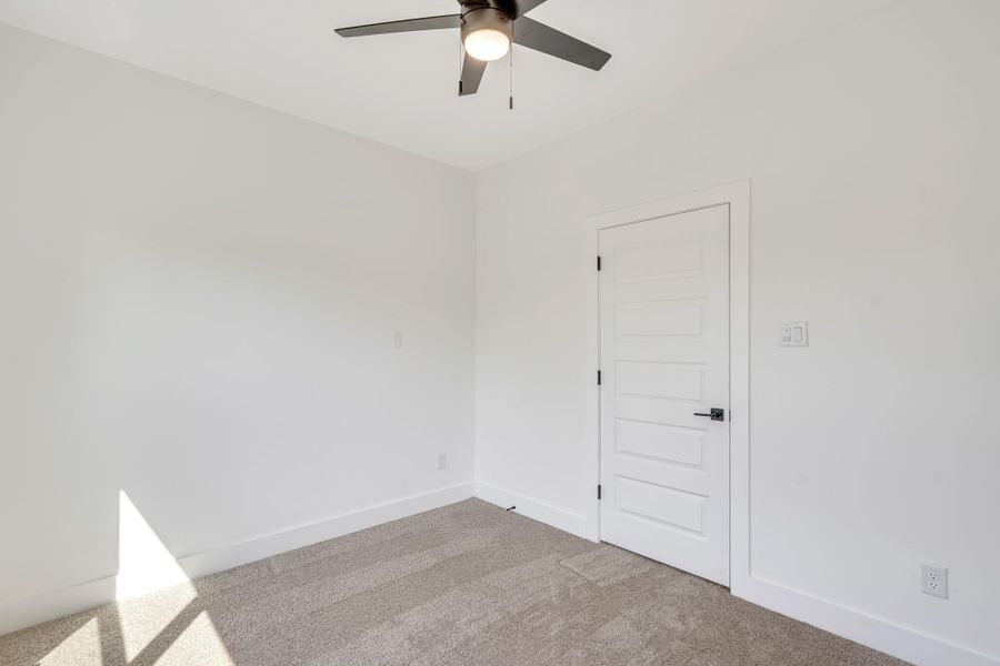 Alternate view of the third upstairs bedroom highlighting the clean, modern finishes, plush carpeting, and sleek black hardware that continues the home’s cohesive design.