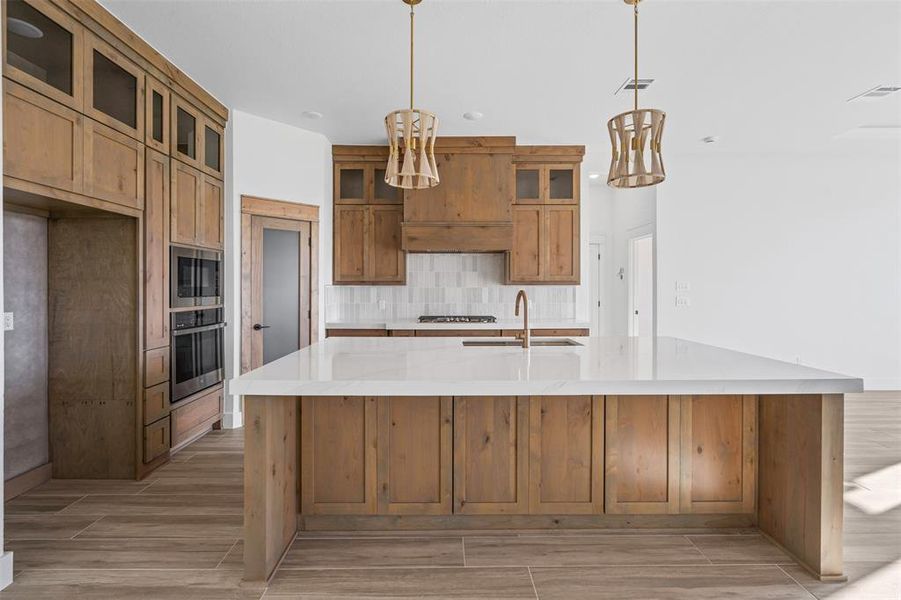 Kitchen with sink, light wood-type flooring, decorative light fixtures, and appliances with stainless steel finishes