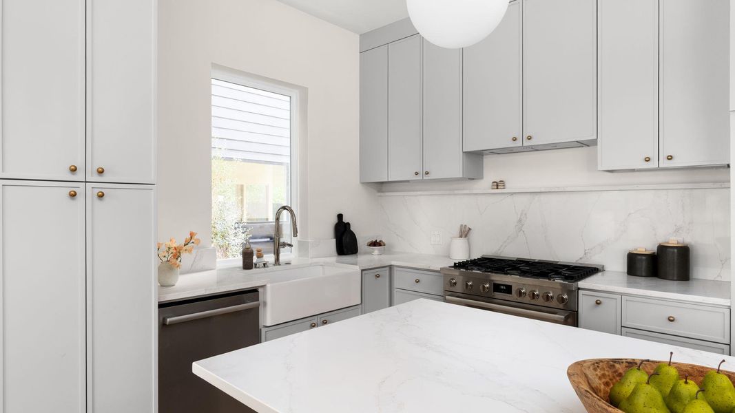 Kitchen featuring stainless steel appliances, light stone countertops, and decorative backsplash