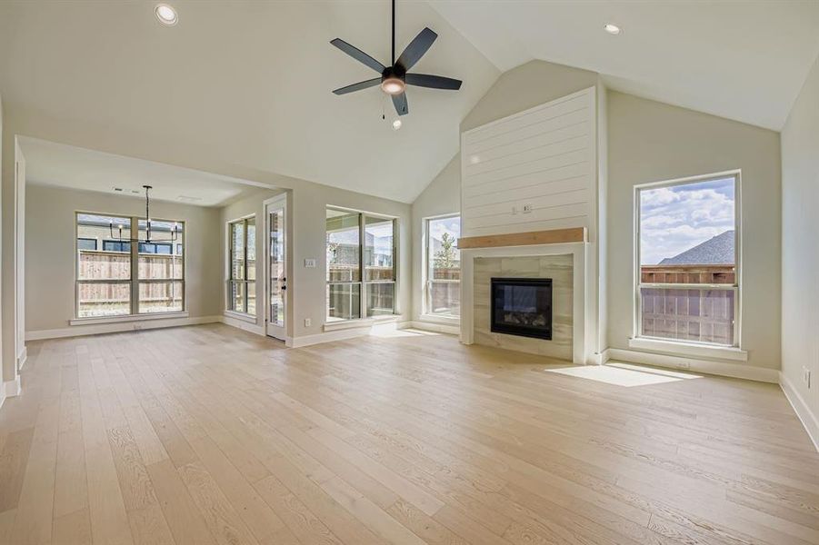 Unfurnished living room with high vaulted ceiling, light wood-style floors, a tiled fireplace, recessed lighting, and a ceiling fan
