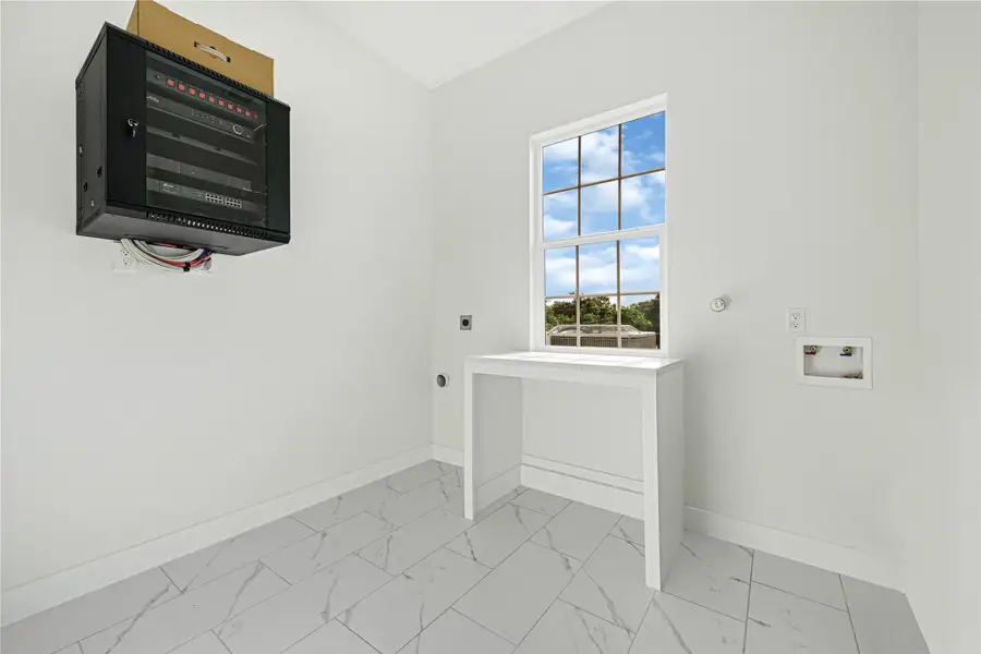 Bright and modern laundry room with ample natural light and sleek tile flooring, perfect for efficient and stylish laundry days.