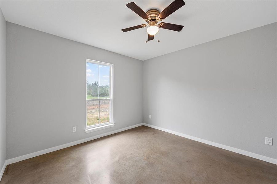 Unfurnished room featuring baseboards, a ceiling fan, and concrete flooring
