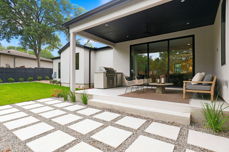 Covered patio with an outdoor kitchen, modern sliding glass doors, a ceiling fan, and recessed lighting