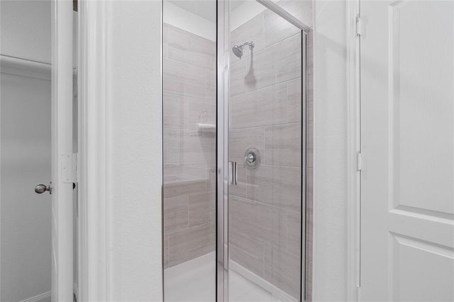 Additional view of the primary bathroom featuring a walk-in shower with tile surround, high ceilings, custom paint, sleek and dark modern finishes.