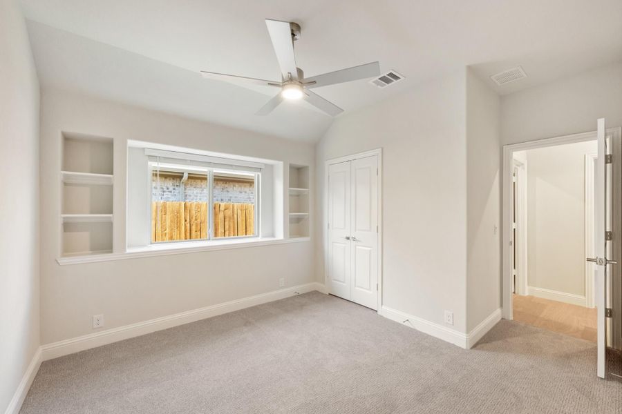 Empty bedroom with vaulted ceiling, ceiling fan, built-in shelves, and carpeted floor Empty bedroom with vaulted ceiling, ceiling fan, built-in shelves, and carpeted floor