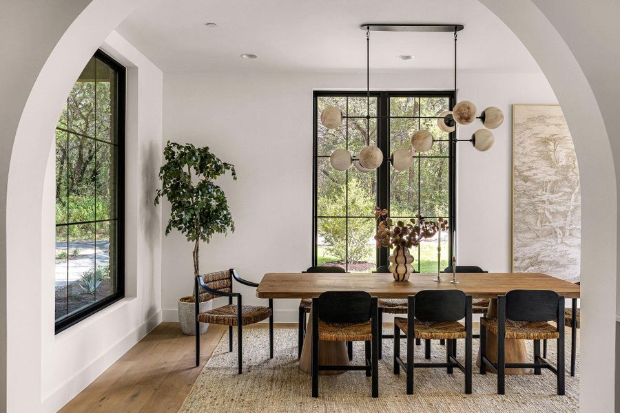 Elegant arches frame a sophisticated dining area beyond a sleek kitchen island with an integrated sink.