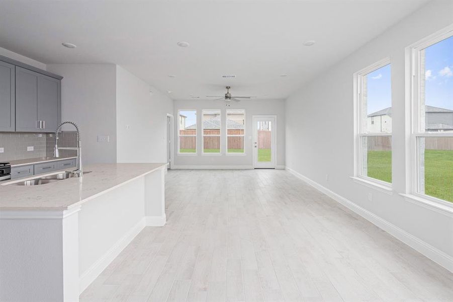 Kitchen with light wood finished floors, gray cabinets, decorative backsplash, a sink, and baseboards