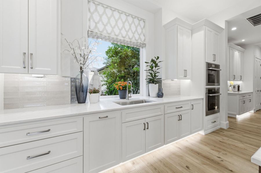 Kitchen featuring decorative backsplash, white cabinets, light wood finished floors, recessed lighting, and light stone countertops