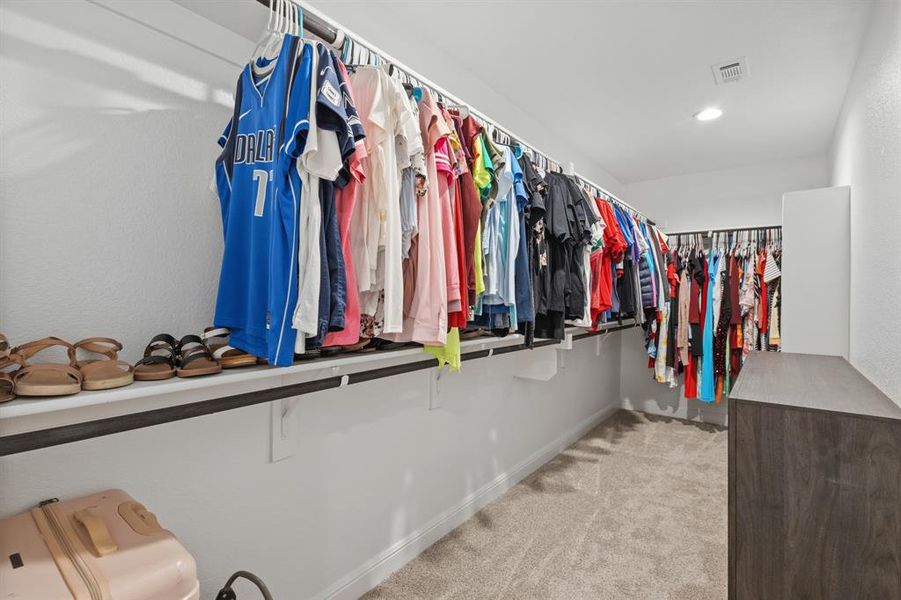 Expansive walk-in closet featuring multiple clothing rods, integrated shelving, recessed lighting, and soft carpet flooring Expansive walk-in closet featuring multiple clothing rods, integrated shelving, recessed lighting, and soft carpet flooring