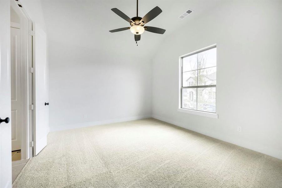 Neutral-toned carpeted room featuring a vaulted ceiling with a ceiling fan and overhead lighting Neutral-toned carpeted room featuring a vaulted ceiling with a ceiling fan and overhead lighting