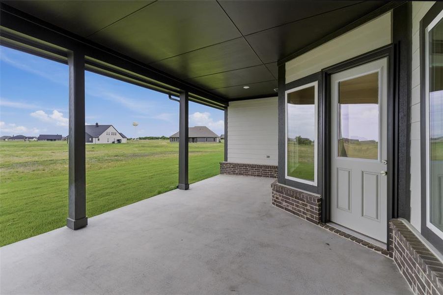 Covered concrete patio featuring dark support columns and a dark soffit ceiling