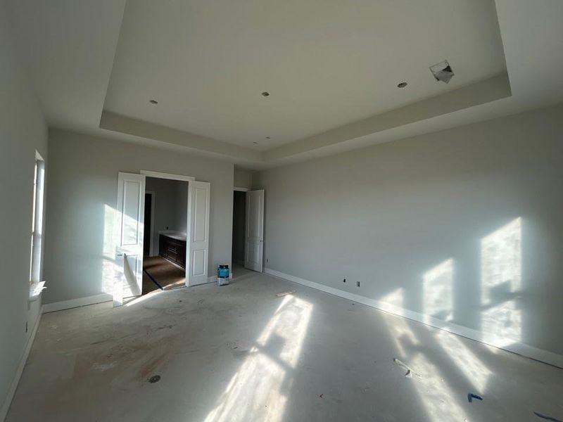 Unfurnished bedroom with a tray ceiling and baseboards