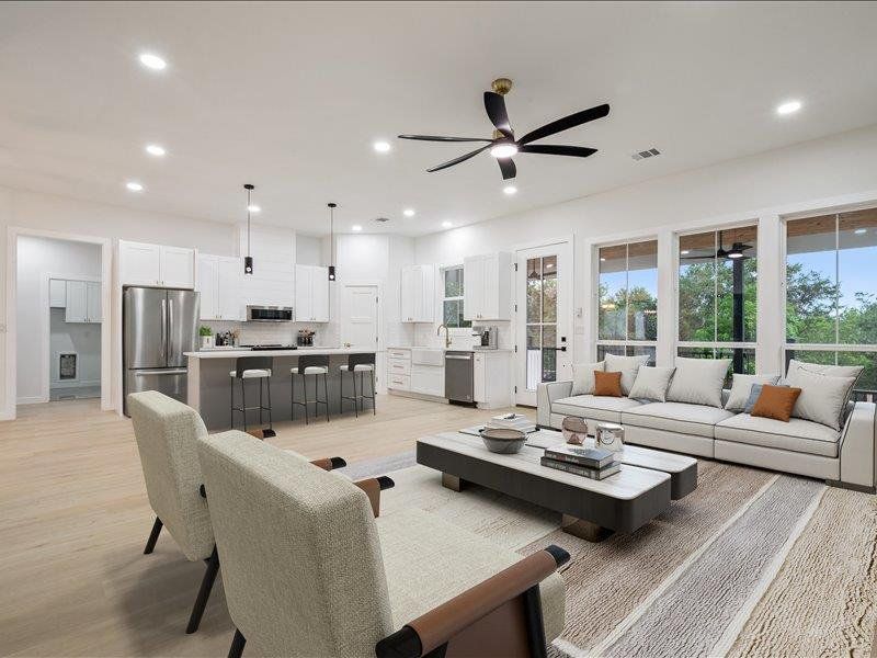 The open-concept living area features light-toned flooring, recessed lighting, and a contemporary ceiling fan