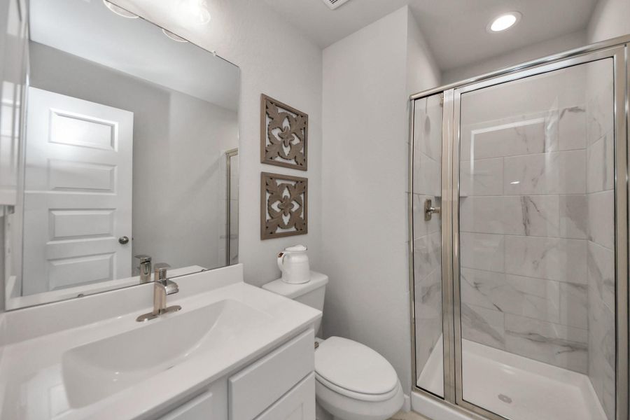 Secondary bath features tile flooring, walk-in shower with tile surround, light stained wood cabinets, beautiful light countertop. Secondary bath features tile flooring, walk-in shower with tile surround, light stained wood cabinets, beautiful light countertop.