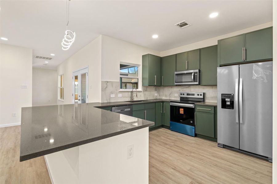 Designer kitchen with sleek cabinetry, quartz countertops, and stainless appliances.