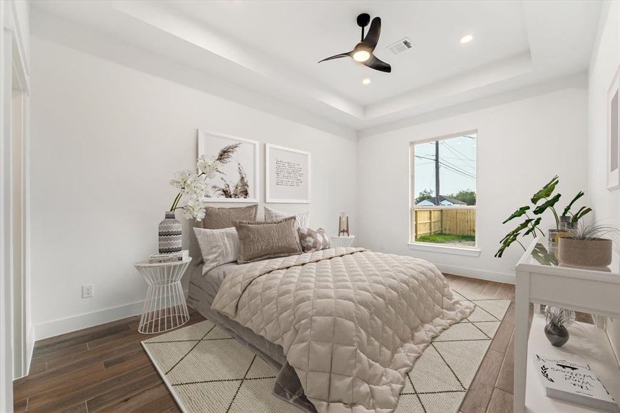 Welcome to the primary bedroom, which boasts a tray ceiling, a modern ceiling fan, and recessed lighting.