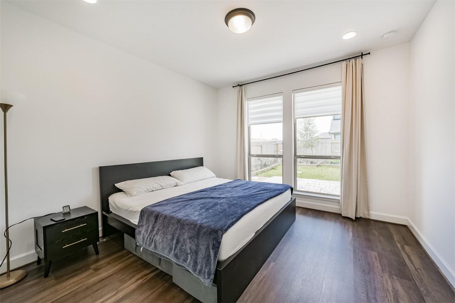 A second bedroom located downstairs, featuring recessed lighting and elegant window treatments. A second bedroom located downstairs, featuring recessed lighting and elegant window treatments.