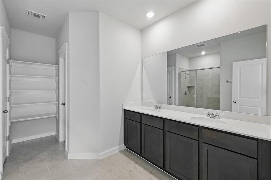 Bathroom featuring double vanity, a shower stall, a walk in closet, and recessed lighting