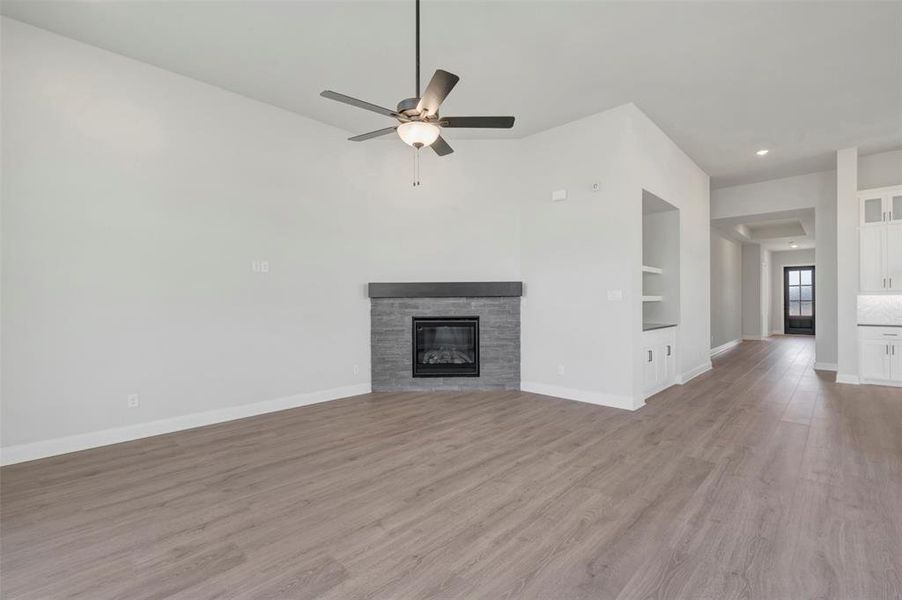 Unfurnished living room featuring a stone fireplace, wood finished floors, ceiling fan, and recessed lighting