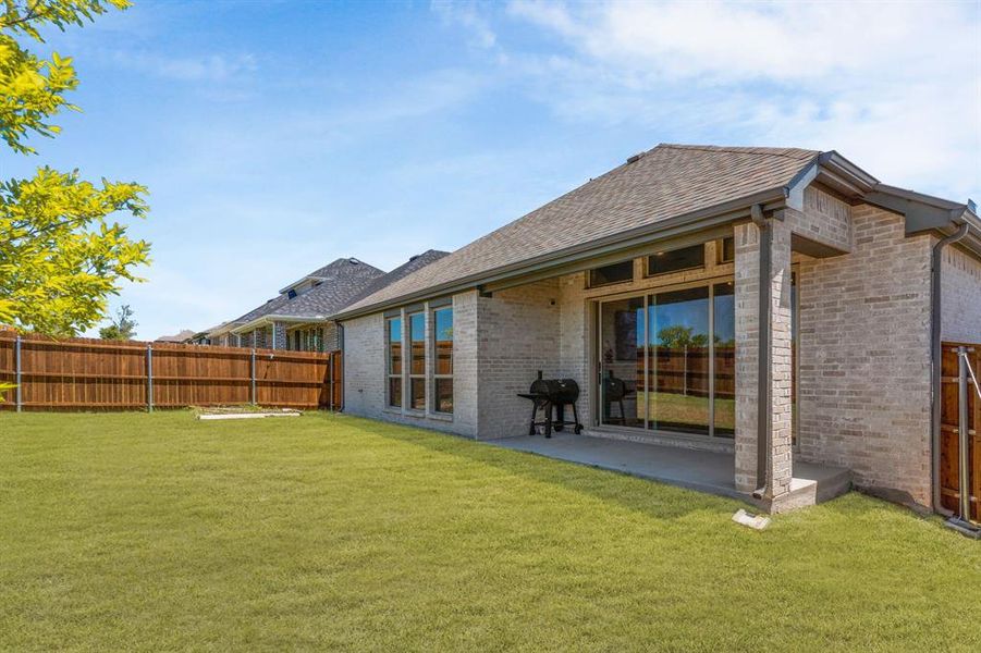 Back of property featuring brick siding, roof with shingles, and a patio Back of property featuring brick siding, roof with shingles, and a patio