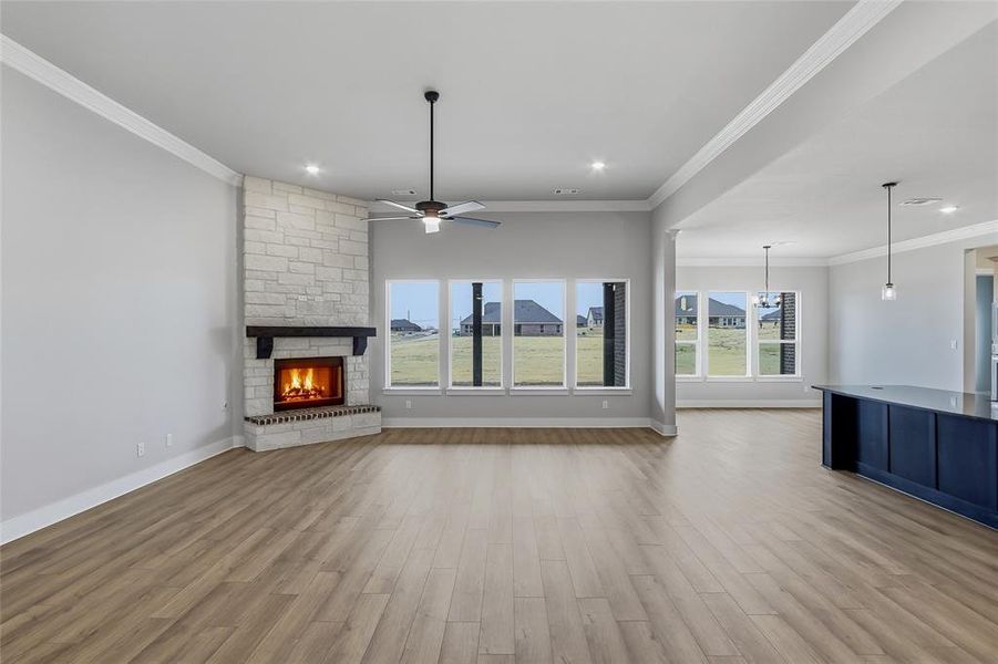 Unfurnished living room featuring a fireplace, light wood-style flooring, ornamental molding, a ceiling fan, and recessed lighting