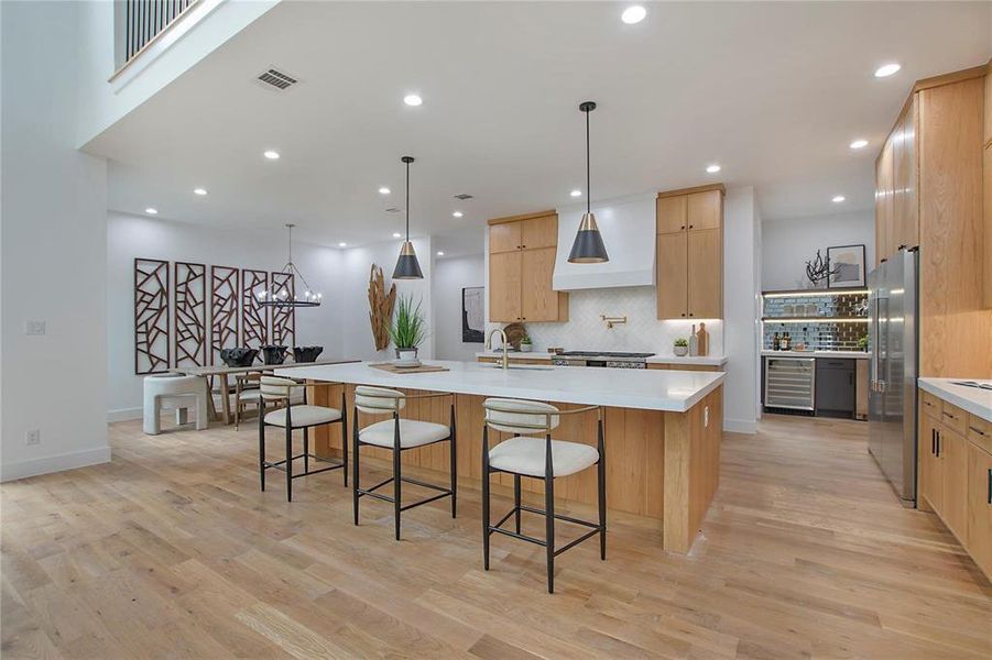 Kitchen featuring beverage cooler, freestanding refrigerator, backsplash, a large island, and recessed lighting Kitchen featuring beverage cooler, freestanding refrigerator, backsplash, a large island, and recessed lighting