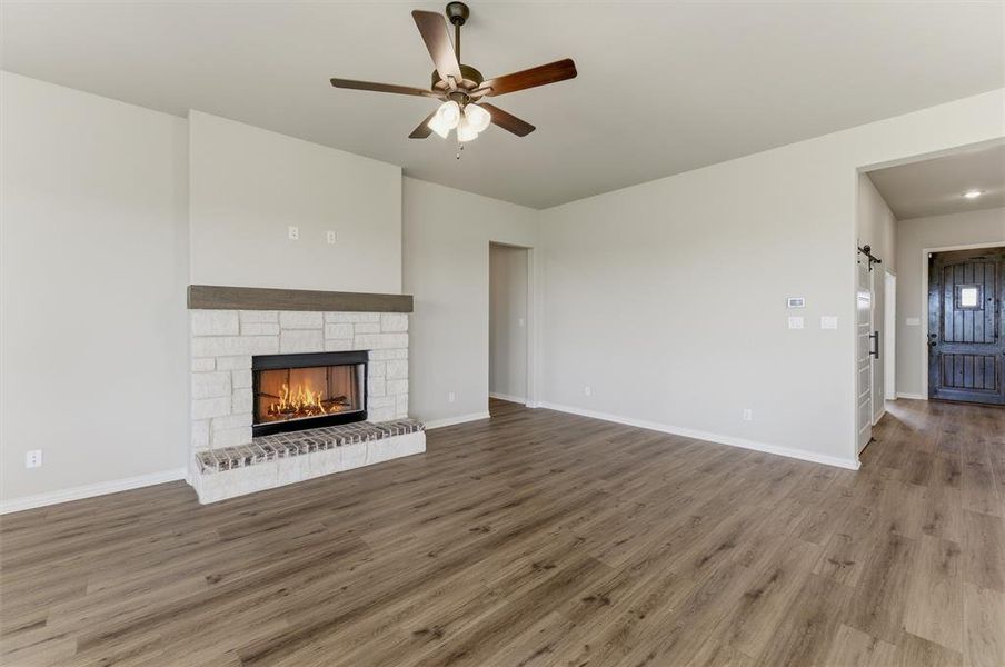 Unfurnished living room with ceiling fan, a fireplace, and dark wood-style flooring Unfurnished living room with ceiling fan, a fireplace, and dark wood-style flooring