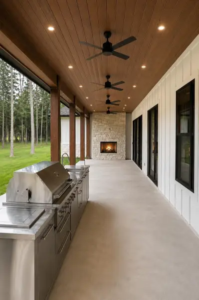 Expansive covered patio featuring a full outdoor kitchen, tongue and groove stained wood ceiling, multiple ceiling fans, and a stone fireplace overlooking peaceful wooded views. Virtually Staged. Expansive covered patio featuring a full outdoor kitchen, tongue and groove stained wood ceiling, multiple ceiling fans, and a stone fireplace overlooking peaceful wooded views. Virtually Staged.