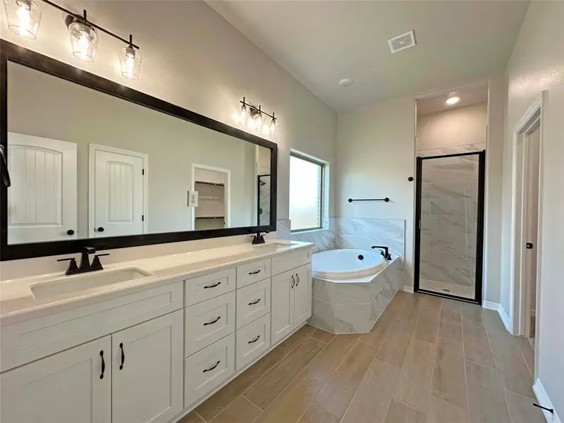Full bathroom with a shower stall, a garden tub, double vanity, wood tiled floors, and recessed lighting Full bathroom with a shower stall, a garden tub, double vanity, wood tiled floors, and recessed lighting