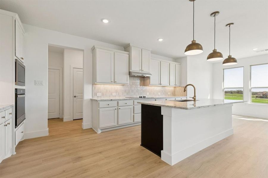Kitchen featuring decorative backsplash, light stone counters, pendant lighting, white cabinetry, and recessed lighting
