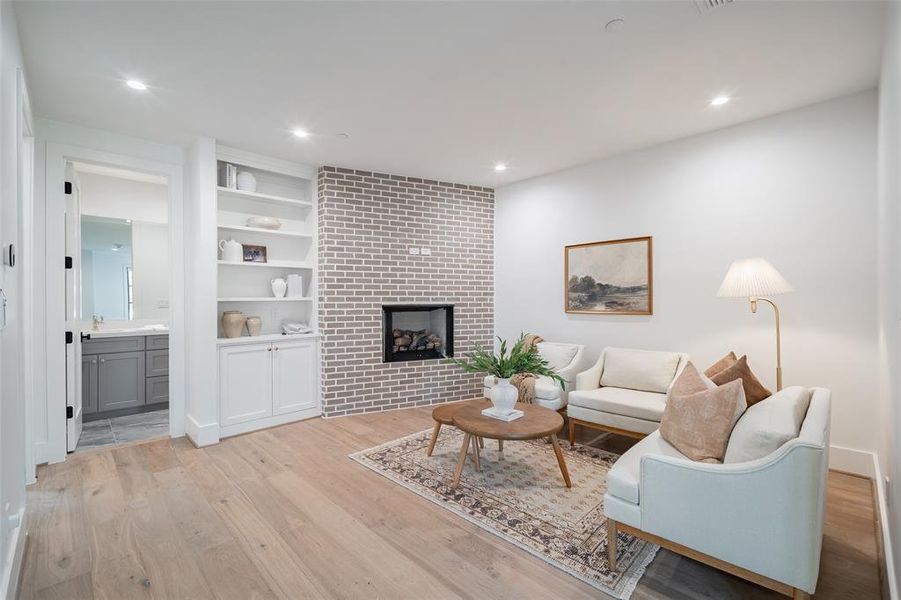 Living room featuring built in shelves, a fireplace, light hardwood / wood-style floors, and sink