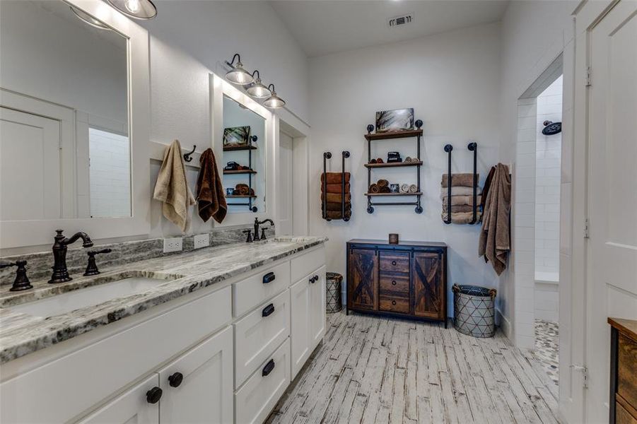 Bathroom featuring dual vanity, hardwood / wood-style flooring, and a shower Bathroom featuring dual vanity, hardwood / wood-style flooring, and a shower