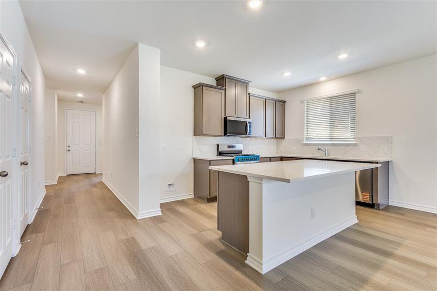 Kitchen featuring appliances with stainless steel finishes, light wood-style floors, backsplash, recessed lighting, and a center island Kitchen featuring appliances with stainless steel finishes, light wood-style floors, backsplash, recessed lighting, and a center island