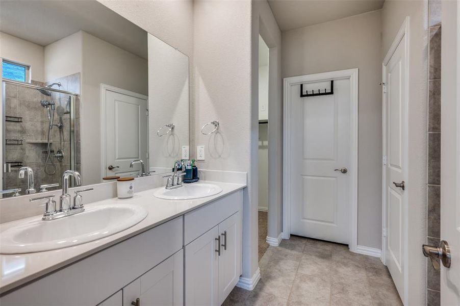 Bathroom featuring double vanity, a shower stall, and light tile patterned flooring