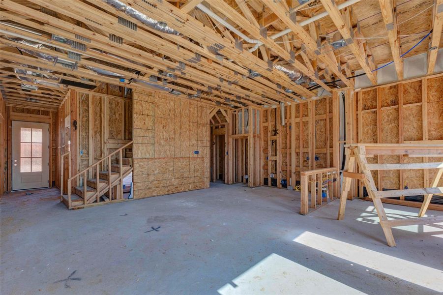 Main-level interior framing view highlighting the staircase, future living area, kitchen placement, and open layout. Exposed beams, electrical rough-ins, and structural framing give buyers a clear look at the home’s construction quality and flow, while the large open space helps showcase the potential for everyday living and entertaining. Main-level interior framing view highlighting the staircase, future living area, kitchen placement, and open layout. Exposed beams, electrical rough-ins, and structural framing give buyers a clear look at the home’s construction quality and flow, while the large open space helps showcase the potential for everyday living and entertaining.