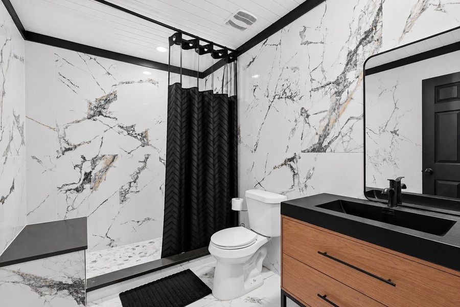 Luxurious bathroom showcasing elegant marble-patterned tile and sleek modern fixtures.