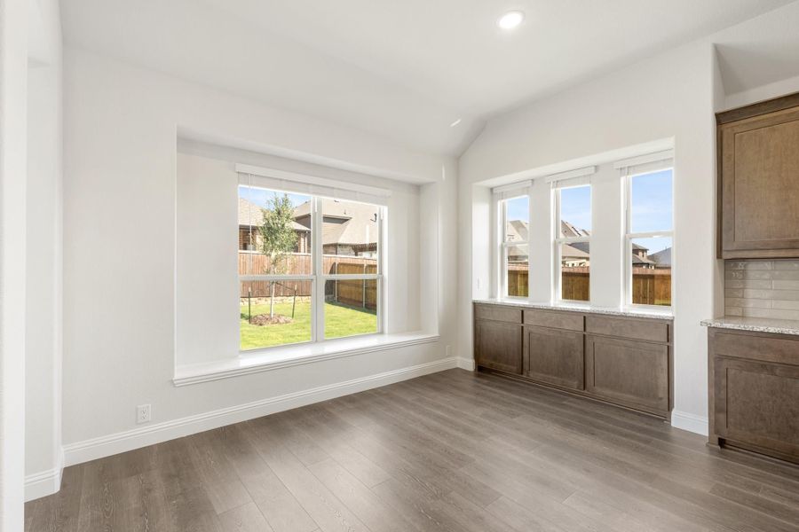 Bright dining area with hardwood floors, large windows, and dark wood built-in cabinets along the wall Bright dining area with hardwood floors, large windows, and dark wood built-in cabinets along the wall
