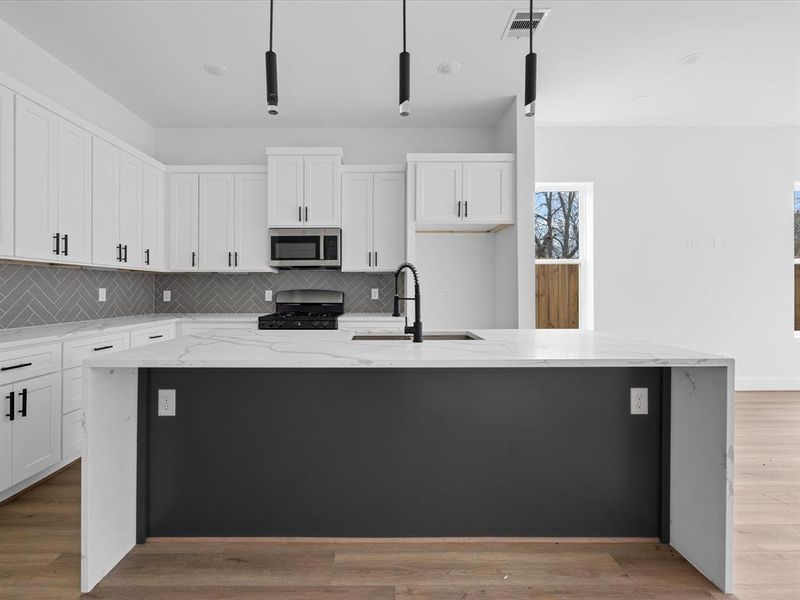 This photo showcases a bright, modern entryway with a wooden floor leading into an open living area. The space features a white front door with a window, a storage closet, and large glass doors opening to a fenced backyard, providing ample natural light.