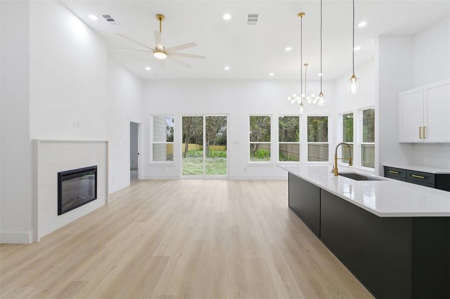 Kitchen with a glass covered fireplace, white cabinetry, recessed lighting, decorative light fixtures, and dark cabinetry